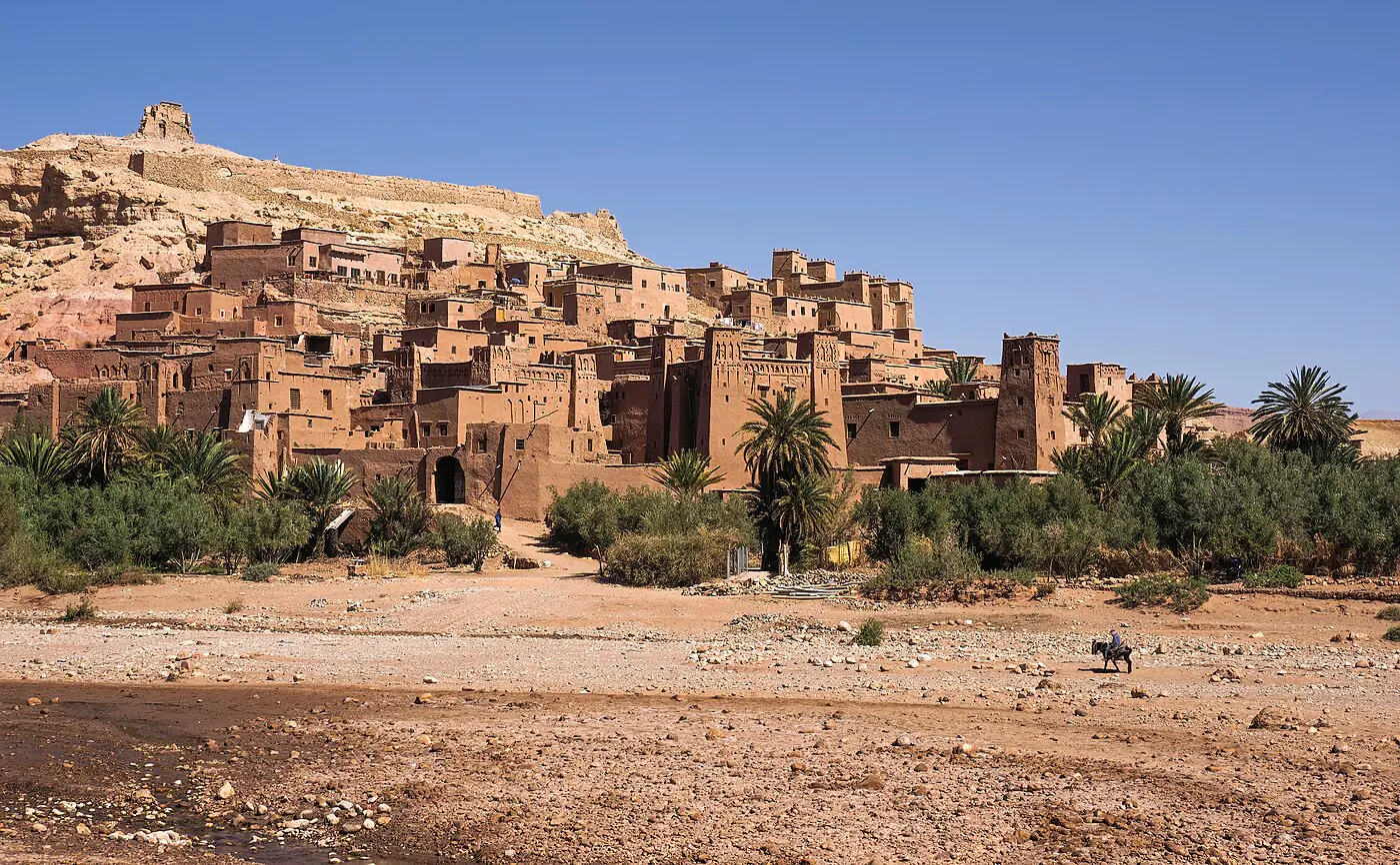 The earthen ksar of Aït Ben Haddou rising above palms and the dry riverbed